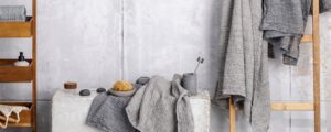 Organic waffle linen towels in grey shades, bamboo toothbrushes, bathroom zero waste accessories in contemporary bathroom interior. Daily body care, spa and wellness zero waste bathroom concept
